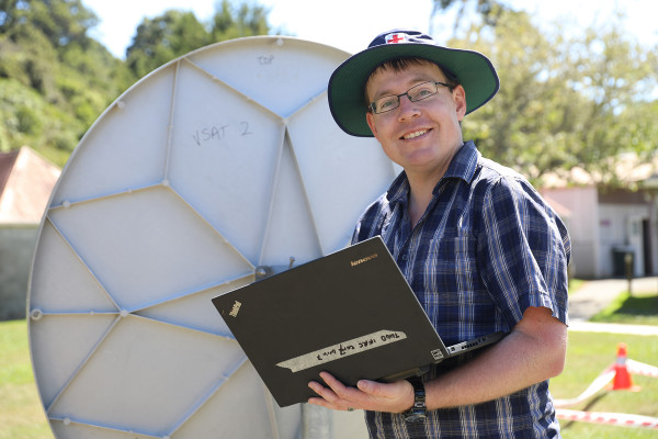 A man standing in front of a satellite dish.