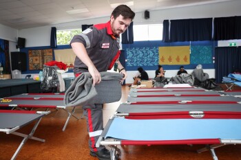 A Red Cross volunteer sets up stretcher beds in an evacuation centre.