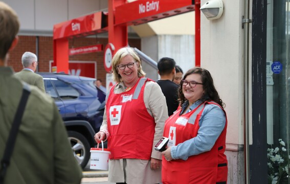 Two women standing together wearing fundraising jackets.