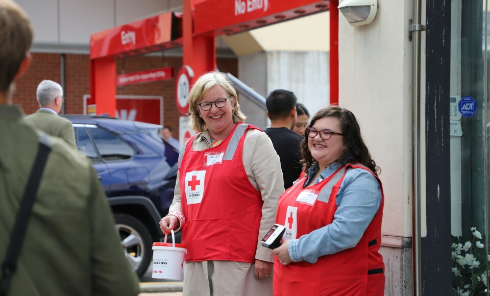 Two women standing together wearing fundraising jackets.