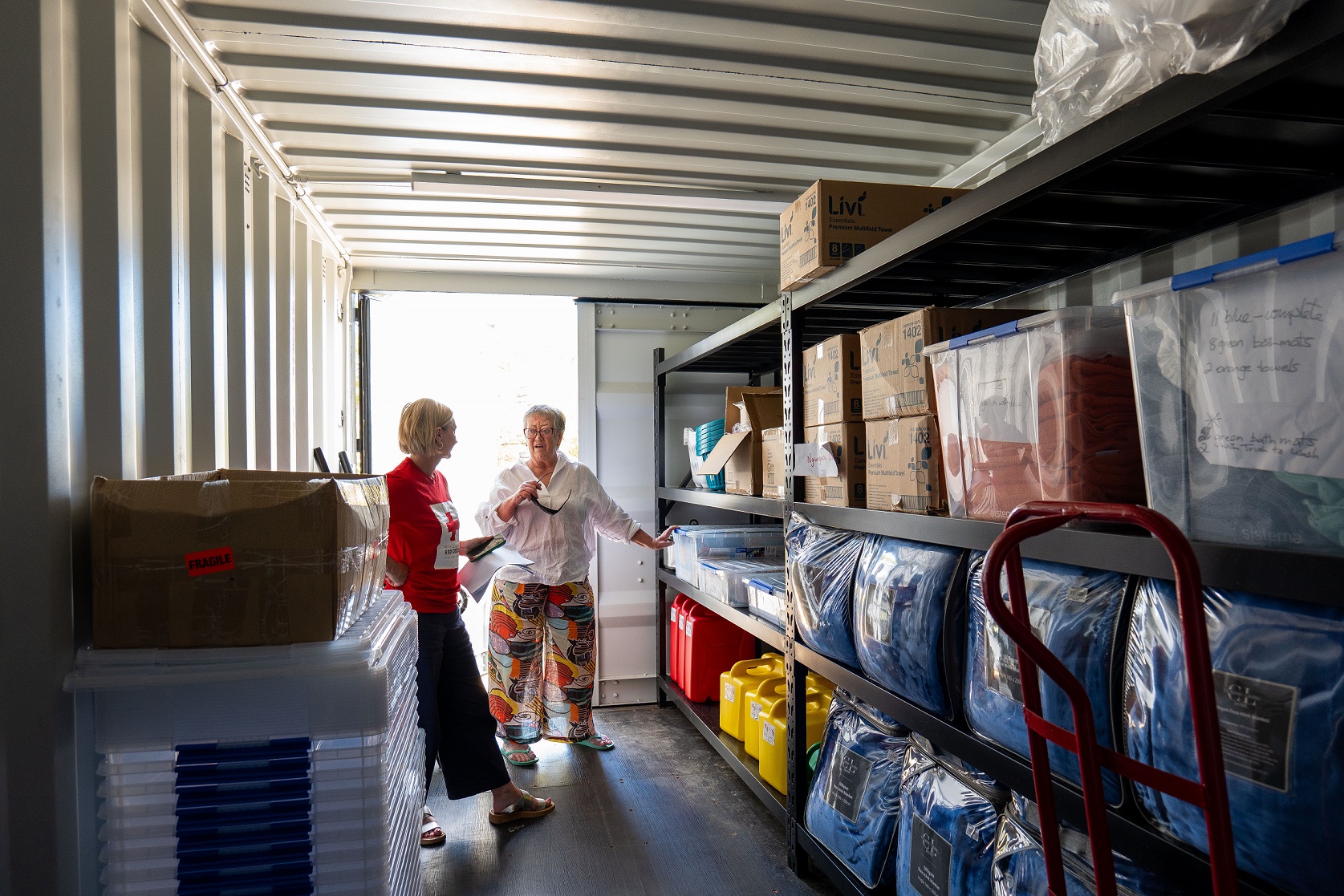 Two women talking in a supplies pod at Ngunguru Marae